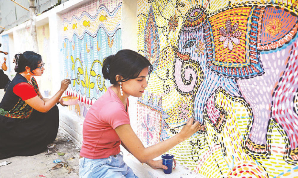 দেয়ালে নকশিকাঁথার মোটিফ আঁকছেন শিল্পীরা